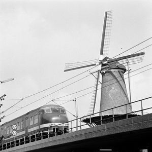857531 Gezicht op de molen De Roos aan de Phoenixstraat te Delft, met op de voorgrond een electrisch treinstel mat. ...
